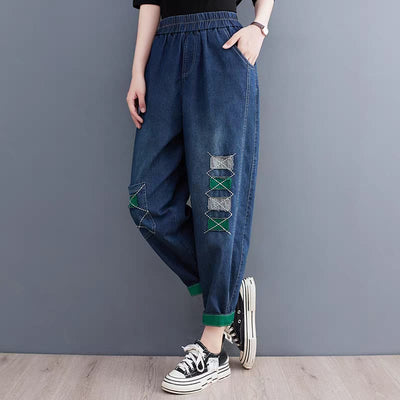 Person wearing blue denim pants with decorative patches against a gray background